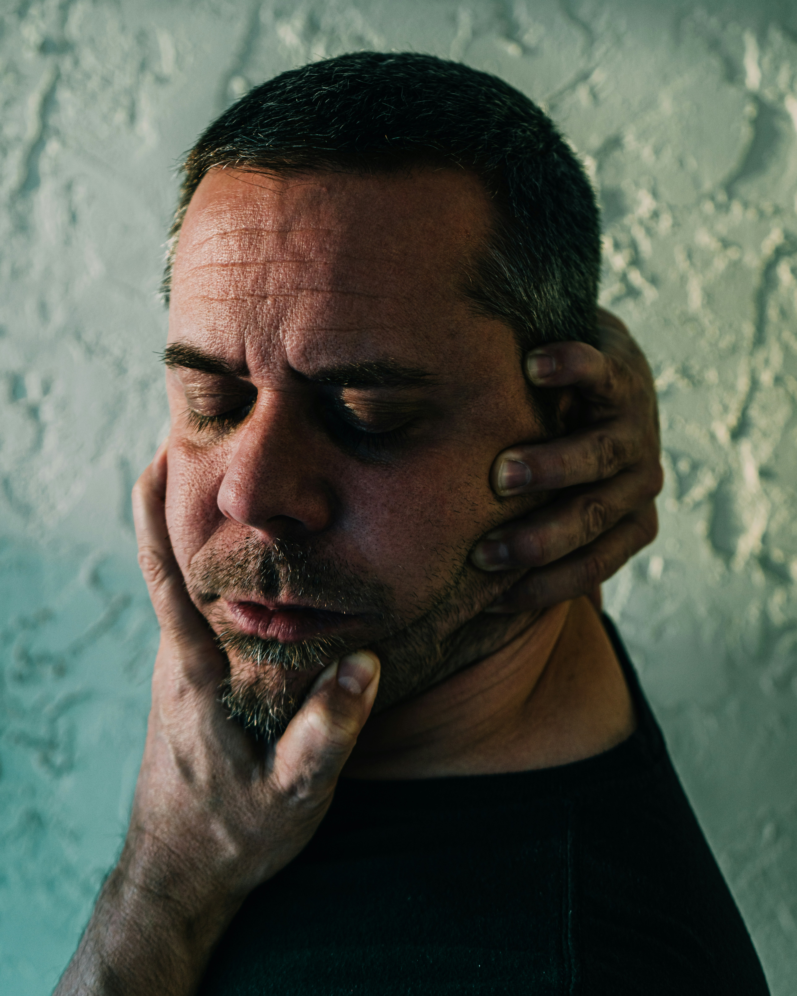 photograph of man holding face